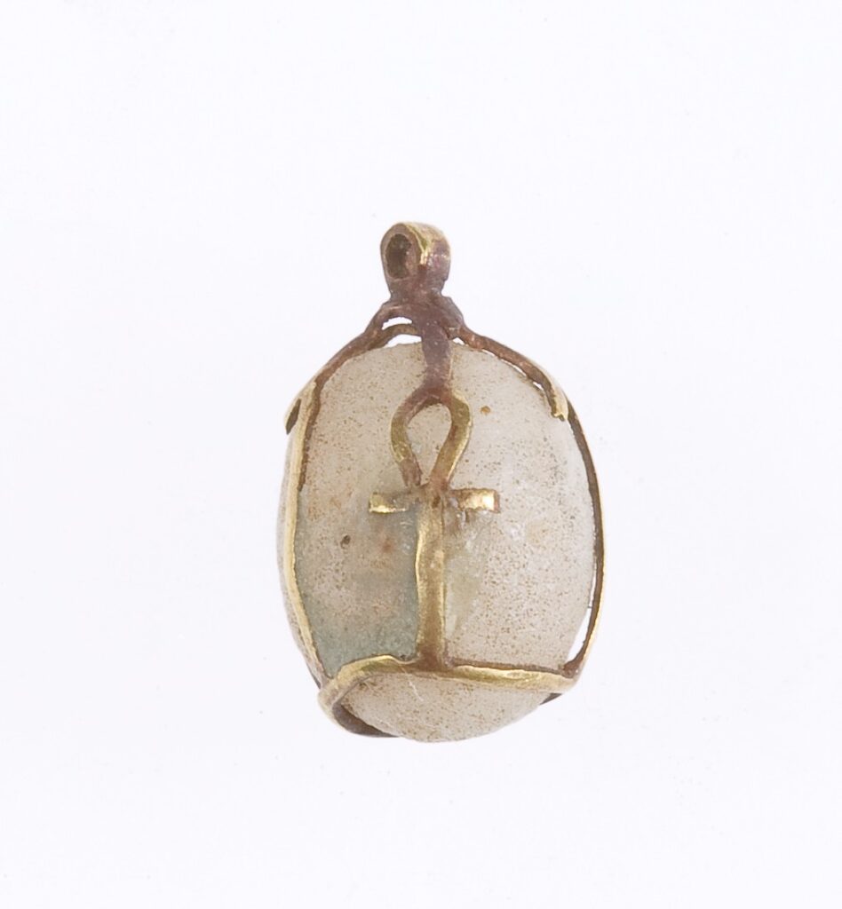 Owalny jasny amulet z wyrytym złotym znakiem ankh na wypukłej powierzchni