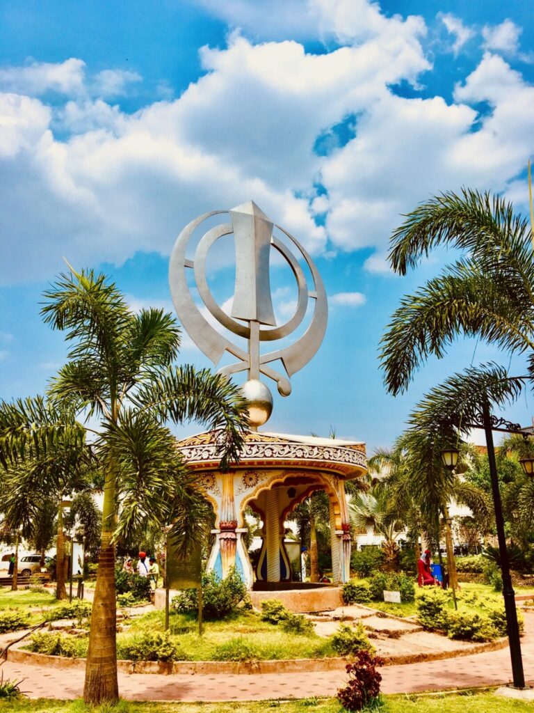 Khanda przy gurdwarze w Bidarze Metalowa rzeźba symbolu khanda z obosiecznym mieczem, pierścieniem i dwiema szablami, na tle palm