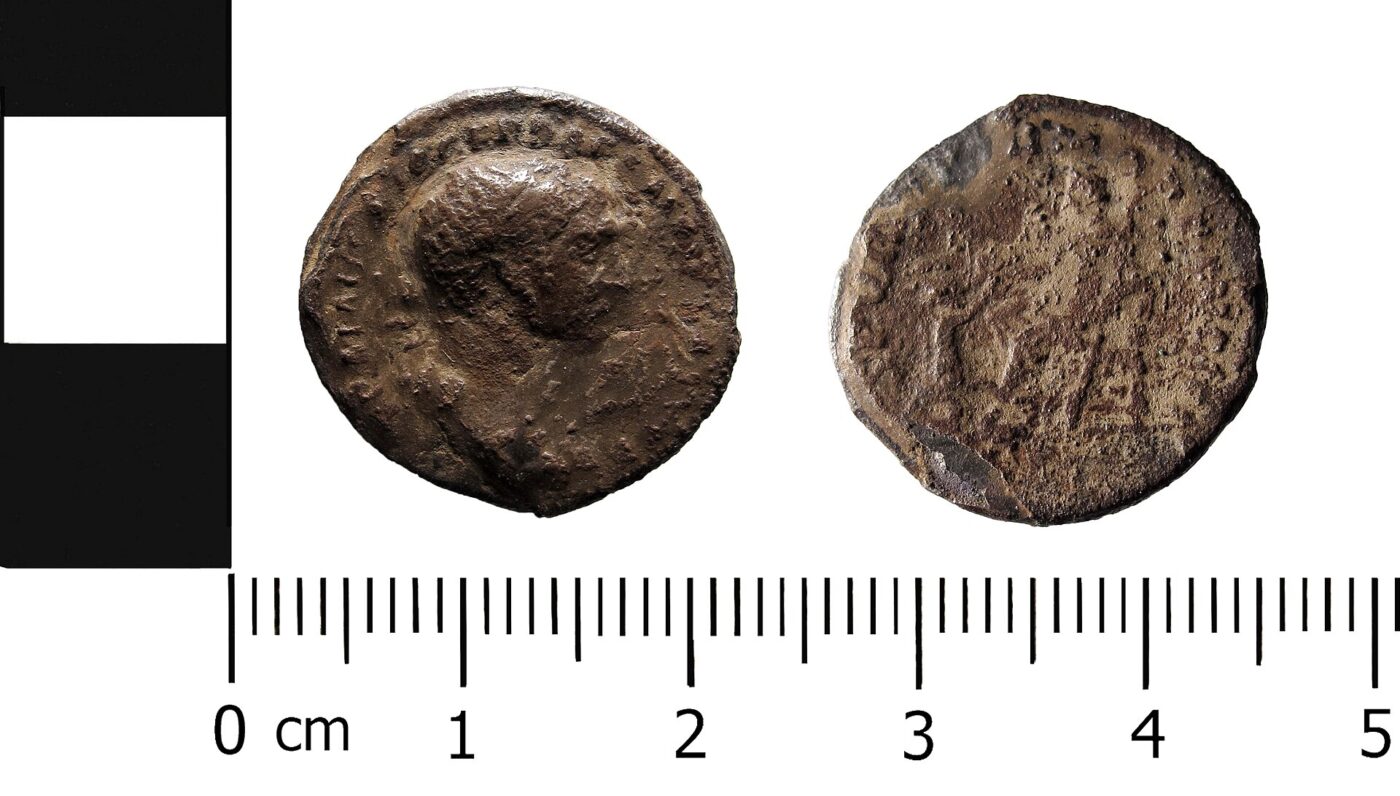 Srebrny denar Trajana z lat 98-117 przedstawiający siedzącą boginię Pax z gałązką oliwną, sfotografowany z podziałką milimetrową